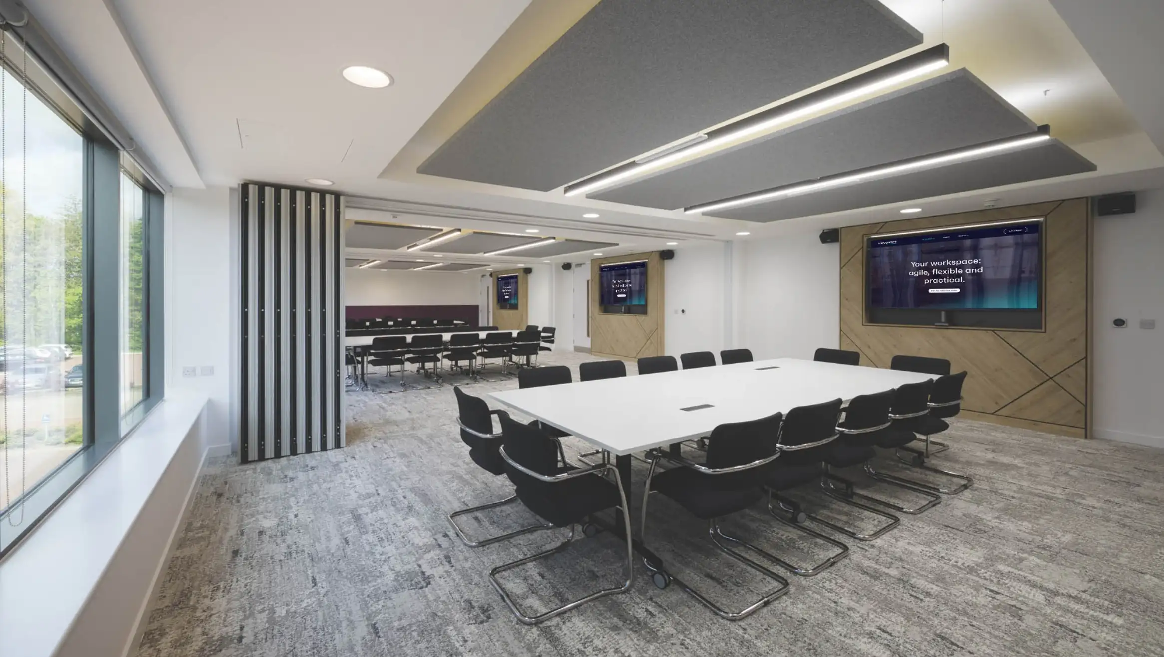 Conference meeting area with mutiple tables and screens